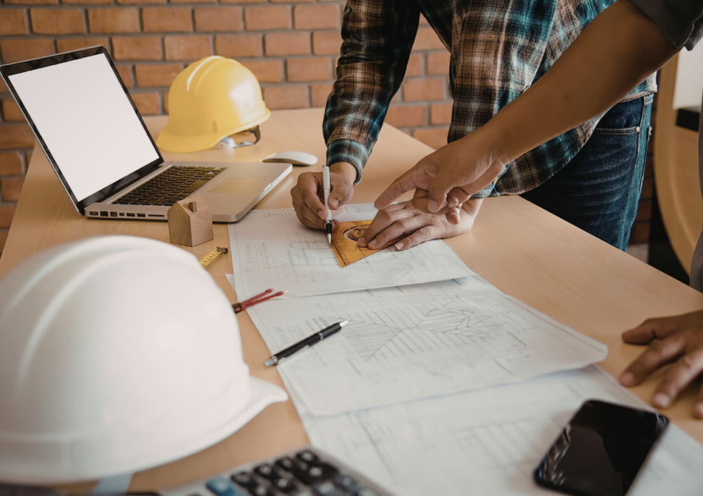 Builder and client reviewing architectural blueprints together — building from your own plans vs using a design-build team in Gulf Shores AL