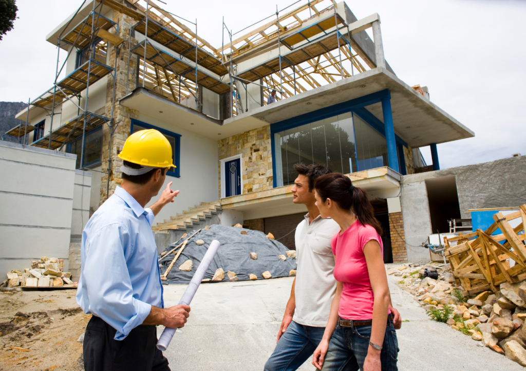 Custom home builder discussing construction progress with homeowners at a job site — client communication during a Gulf Coast home build