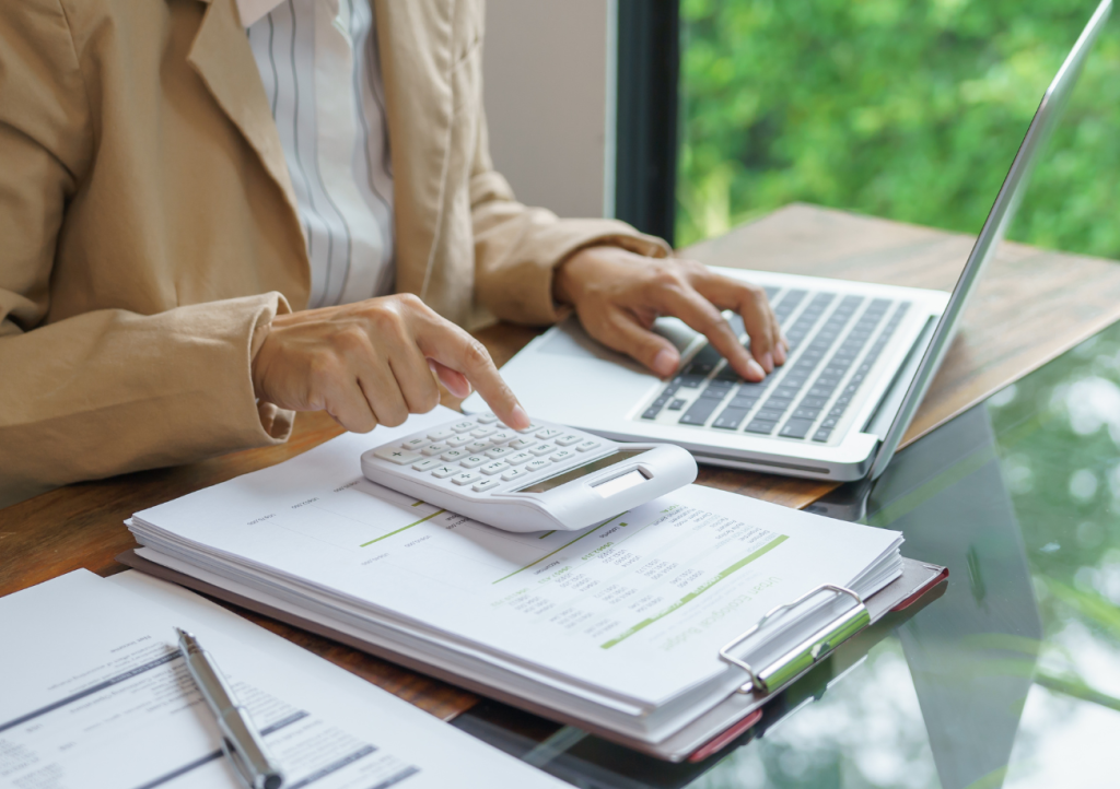 Homeowner reviewing custom home building allowances and budget documents with a calculator and laptop