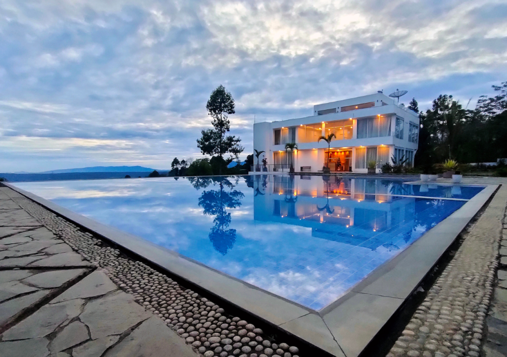Modern custom home with large inground pool and stone deck at twilight — pool and home construction timeline considerations for Gulf Coast design-build projects
